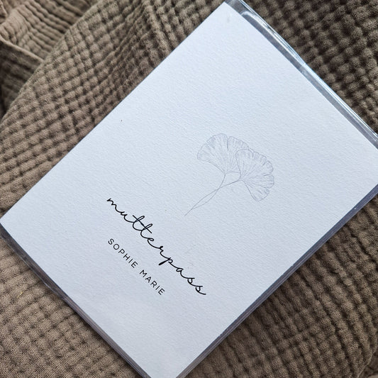 Personalisierte Mutterpasshülle mit minimalistischem Ginkgo-Design – handgemacht, stilvoll präsentiert auf weichem Stof