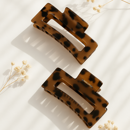 Braune Haarklammer im Tortoise-Design aus glänzendem Acetat auf hellem Hintergrund mit getrockneten Blumen – stilvolle Haaraccessoires für Damen.