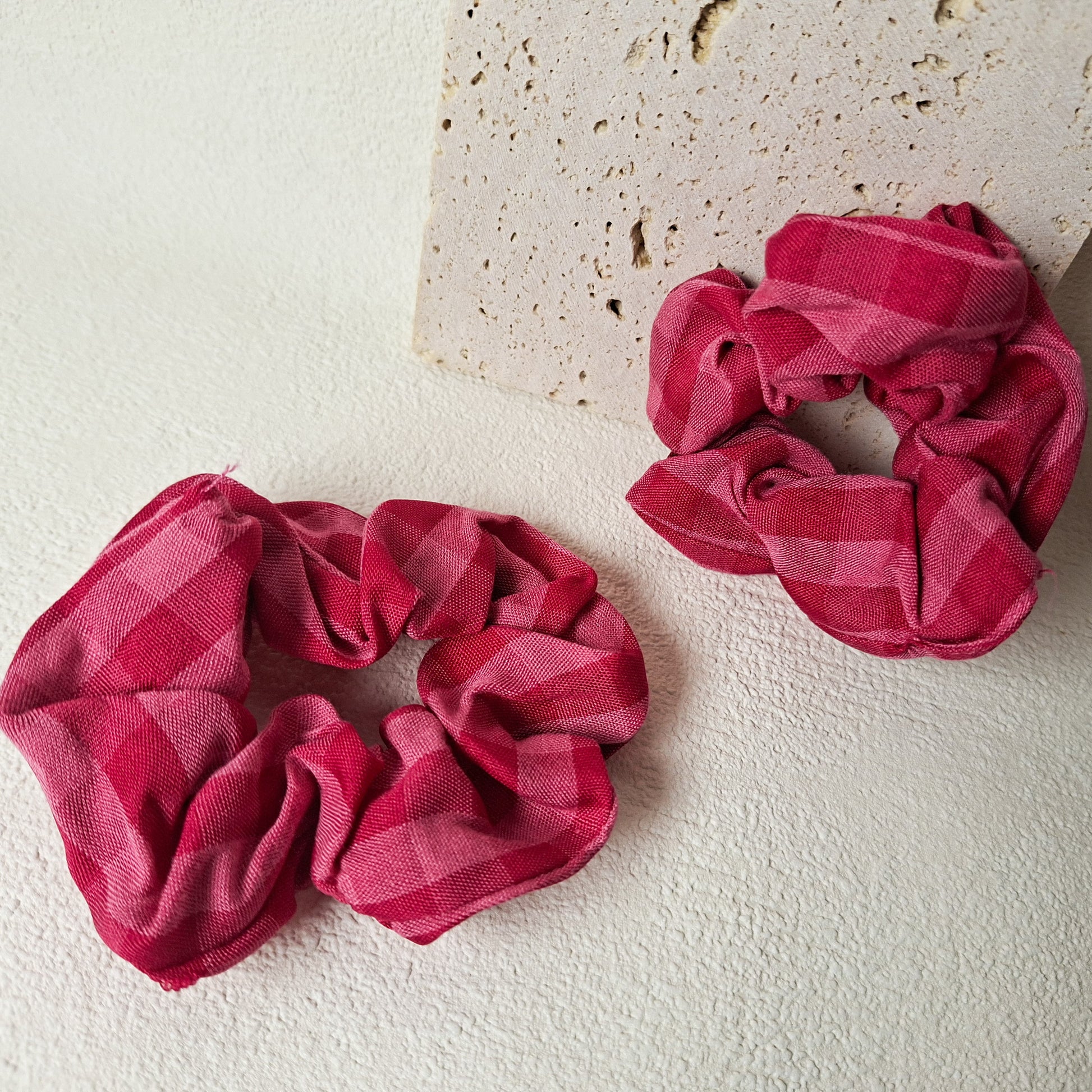 Kariertes Stoff-Scrunchie in Pink und Rosa, weiches Haargummi als Haaraccessoire auf hellem Untergrund